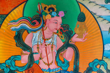 Coorg, India - October 29, 2013: Inside Padmasambhava Vihara of Namdroling Buddhist Monastery. Detail of wall painting. Vivid colors. Bare breasted goddess or Bodhisattva closeup.のeditorial素材