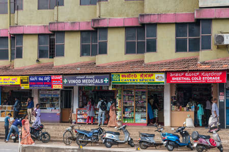 Madikeri, India - October 31, 2013: Row of five retail stores with colorful billboars at ground...