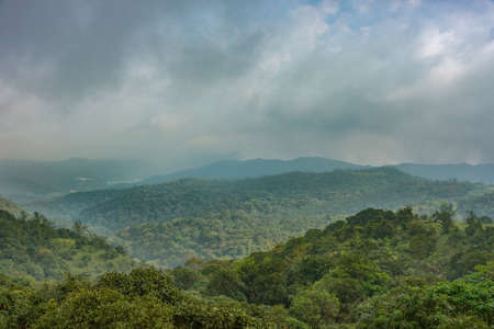 Talakaveri, India - October 31, 2013: Blue and gray clouds over the green jungle covered highlands around the spring of the Kaveri River sanctuary.の写真素材