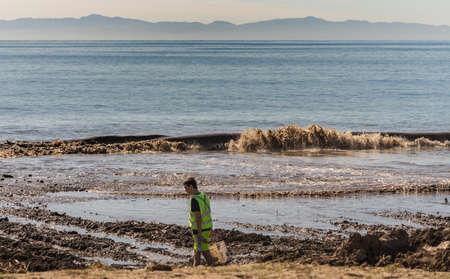Santa Barbara, United States - Febriary 16, 2018: Young man searches debris in off-flooding dirt...