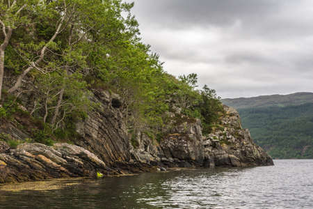Rainy cloudscape and silver water. Forested mountain in back.
