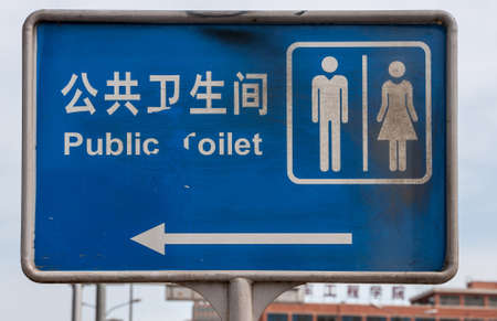 Beijing, China - April 26, 2010: Closeup of blue Public Toilet sign on pole along street shows...