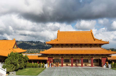 Hacienda Heights, CA, USA - March 23, 2018: Hall of bodhisattvas at Hsi Lai Buddhist Temple under heavy rainy cloudscape. Seen from inside temple complex. Monks in photo.のeditorial素材