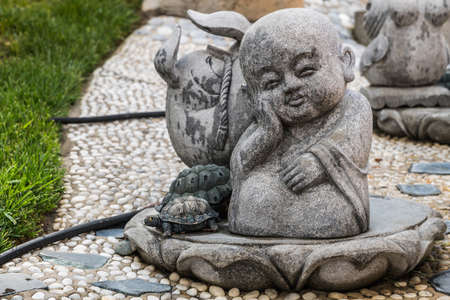 Hacienda Heights, CA, USA - March 23, 2018: Boy novice monk cement statue in garden of Hsi Lai Buddhist Temple. Green grass.のeditorial素材