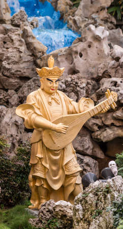 Hacienda Heights, CA, USA - March 23, 2018:  Closeup of golden Dhrtarastra the East Heavenly King in Avalokitesvara garden  at Hsi Lai Buddhist Temple. Brown and blue surroundings.のeditorial素材