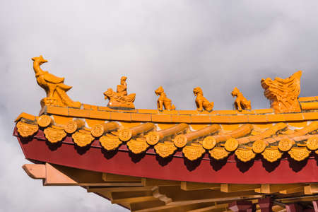 Hacienda Heights, CA, USA - March 23, 2018: Red ochre roof structure of Hsi Lai Buddhist Temple under heavy dark cloudscape. Corner tip with figurine decoration.のeditorial素材