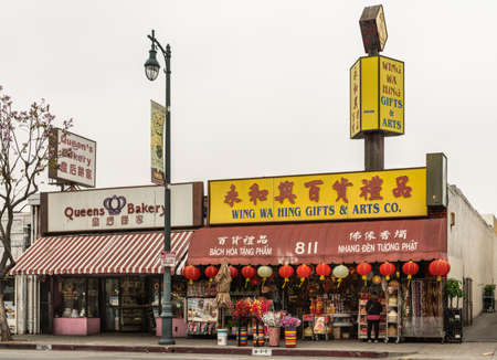 Los Angeles, CA, USA - April 5, 2018: Block with Queens Bakery and Chinese Gift store along Broadway in Chinatown under silver sky. Plenty of colors by advertisements, billboards and merchandise.のeditorial素材