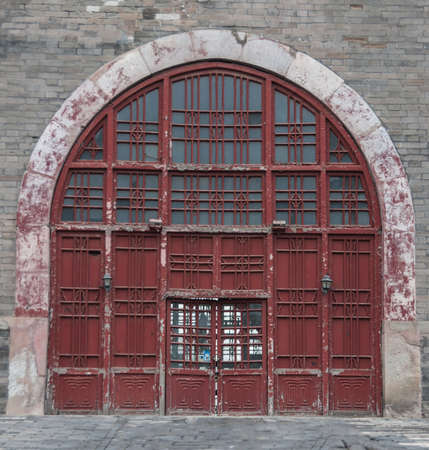 Beijing, China - April 26, 2010: Closeup of large bow-shaped maroon entrance door to under-belly of Bell Tower set in gray stone wall.のeditorial素材