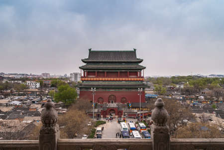 Beijing, China - April 26, 2010: Entire Drum Tower seen from balcony of Bell Tower with the surrounding area, including traffic on streets. Green trees and housing under cloudy sky with some blue.のeditorial素材