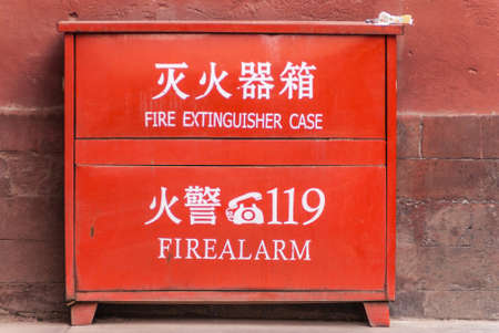Beijing, China - April 27, 2010: Forbidden City. Closeup of red metal Fire Extinguisher box with English and Mandarin message against wall.の写真素材