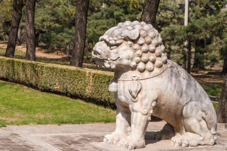 Beijing, China - April 28, 2010: Ming Dynasty Tombs domain, or Ming Changling. Closeup of decorated lion statue along lane of trees.のeditorial素材