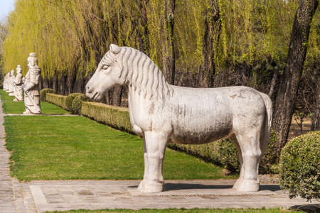 Beijing, China - April 28, 2010: Ming Dynasty Tombs domain, or Ming Changling. Horse statue stands in long line of Mandarin guards against backdrop of green trees.のeditorial素材