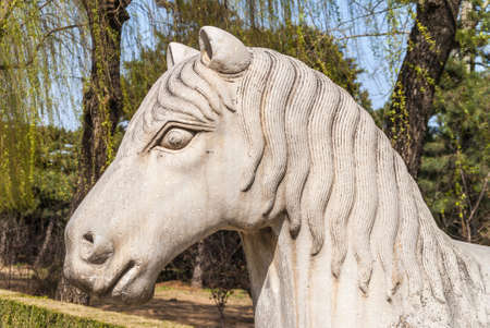Beijing, China - April 28, 2010: Ming Dynasty Tombs domain, or Ming Changling. closeup of head of Horse statue against backdrop of green trees.のeditorial素材