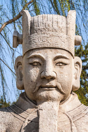 Beijing, China - April 28, 2010: Ming Dynasty Tombs domain, or Ming Changling. Frontal closeup of white-brown head of Mandarin-guard statue against backdrop of green trees.のeditorial素材
