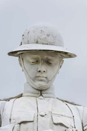 Fort William, Scotland - June 11, 2012: Closeup of white stone war memorial statue on The Parade against gray sky. Shows bust of young soldier in kilt contemplating.のeditorial素材
