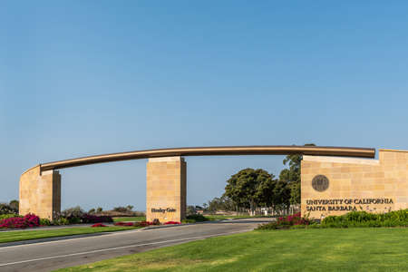 Goleta, California, USA - August 7, 2018: Monumental brown stone Henley Gate into UCSB under blue sky, looking at ocean and plenty of grass and flowers up front.のeditorial素材