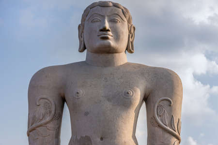 Shravanabelagola, Karnataka, India - November 1, 2013: At the Jain Tirth, closeup of gray granite Giant Bhagwan Bahubali torso statue.  Sunset darker sky.のeditorial素材