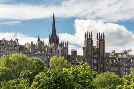 Edinburgh, Scotland, UK - June 13, 2012: New College of University of Edinburgh on market street seen from Scott Monument across green park under blue sky with white clouds.のeditorial素材