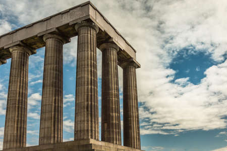 Edinburgh, Scotland, UK - June 13, 2012: Corner of National Monument is series of dark brown pilars against blue sky with white clouds.のeditorial素材