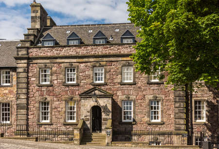Edinburgh, Scotland, UK - June 14, 2012: Brown stone Governors house partialy under green tree and blue sky with white clouds.のeditorial素材