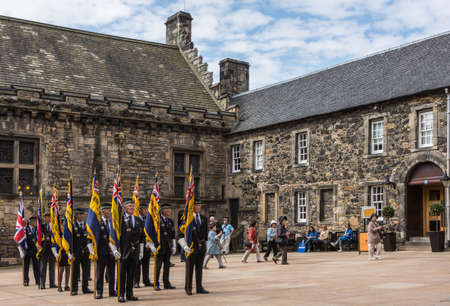 Edinburgh, Scotland, UK - June 14, 2012: Group of veterans with colorful regimental flags ready to enter Scottish National War Memorial at Castle. Brown stone Palace building.のeditorial素材