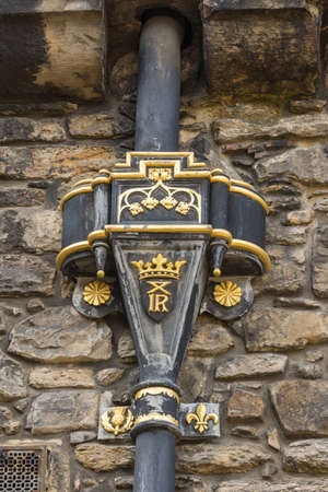 Edinburgh, Scotland, UK - June 14, 2012: Closeup of golden Royal symbols on hopper water collection box on top of downpipe from gutter at Castle.のeditorial素材