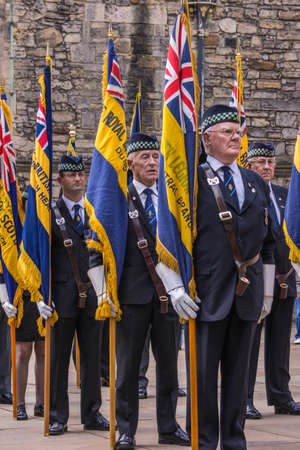 Edinburgh, Scotland, UK - June 14, 2012: Closeup of some of Group of veterans with colorful regimental flags ready to enter Scottish National War Memorial at Castle. Brown stone Palace building.のeditorial素材
