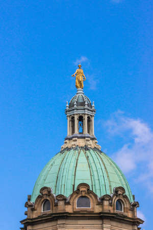 Edinburgh, Scotland, UK - June 14, 2012: Golden statue of female representing Victory on top of the green dome of the Mound building against blue sky. Seen from Royal Mile.のeditorial素材