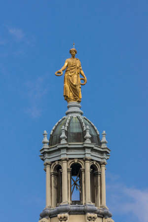 Edinburgh, Scotland, UK - June 14, 2012: Golden statue of female representing Victory on top of tower of the Mound building against blue sky. Seen from Royal Mile.のeditorial素材