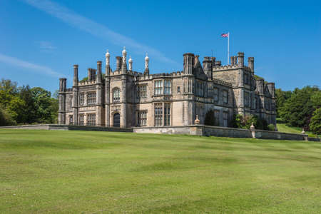 Edinburgh, Scotland, UK - June 14, 2012: Dalmany house, mansion and castle in Tudor revival style on green lawn, with Brittish flag and under blue sky.のeditorial素材