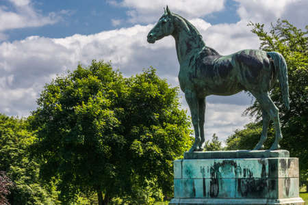 Edinburgh, Scotland, UK - June 14, 2012:Closeup of Horse statue of King Tom looking at Firth of Forth at Dalmeny House. Green trees in back, cloudscape.のeditorial素材