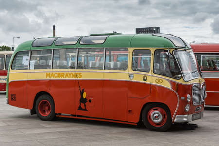 Glasgow, Scotland, UK - June 17, 2012: Along River Clyde, outside Riverside Museum antique red, green and yellow passengers bus under heavy cloudscape.のeditorial素材