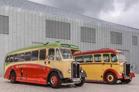 Glasgow, Scotland, UK - June 17, 2012: Along River Clyde, outside Riverside Museum, vintage yellow and red Western and Macbraynes public buses under heavy cloudscape.のeditorial素材