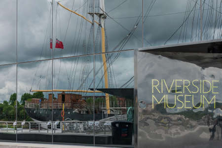 Glasgow, Scotland, UK - June 17, 2012: Tall ship under heavy cloudscape reflected in glass facade of Riverside Museum.のeditorial素材