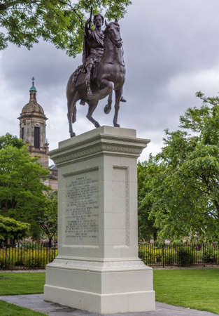 Glasgow, Scotland, UK - June 17, 2012: Prince William III equestrian bronze statue on gray stone pedestal outside Cathedral. Black figure against gray sky. Green foliage around.のeditorial素材