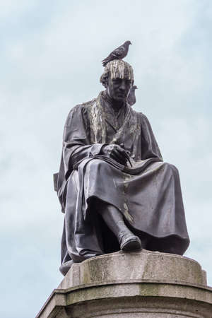 Glasgow, Scotland, UK - June 17, 2012: Closeup of  black bronze james Watt statue on stone pedestal at George Square against light blue sky. Plenty of Pigeon poop and two birds.のeditorial素材