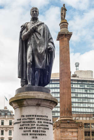 Glasgow, Scotland, UK - June 17, 2012: Closeup of  greenish bronze John Moore statue on stone pedestal at George Square against light blue sky. Sir Walter Scott on his column in back.のeditorial素材