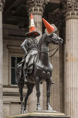 Glasgow, Scotland, UK - June 17, 2012: Closeup of black bronze equestrian statue of Duke of Wellington on Royal Exchange Square in front of Museum of Modern Art. Danger cones on head of man and horse.のeditorial素材