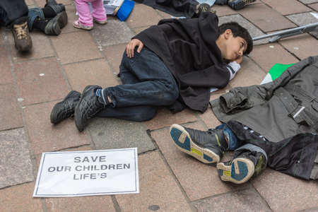Glasgow, Scotland, UK - June 17, 2012: Syrians protest Bashar al-Assad war crimes near Donald Dewar statue. Closeup of Child flat on floor pretending to be dead.のeditorial素材