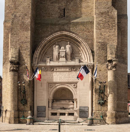 Dunkerque, France - September 16, 2018: Closeup of World wars memorial with flags at base of Belfry of Dunkirk. Fifty shades of brown broken by colors of flags.のeditorial素材