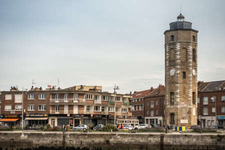 Dunkerque, France - September 16, 2018: Leughenaer brick Clock tower and historic lighthouse on Minck Square at old port of Dunkirk. Street scene with people and cars. Light blue sky.のeditorial素材