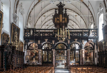 Brugge, Flanders, Belgium - September 19, 2018: Overview of separated chancel of Saint Anna Church in Bruges. Dark wood decorations and plenty of gold. Chairs up front. Altar in back.のeditorial素材