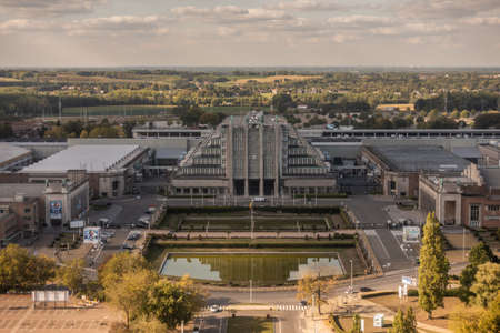Brussels, Belgium - September 25, 2018: The historic world expo halls shot from top of the Atomium monument. Green belt and cloudy sky on horizon. Park with ponds in front.のeditorial素材