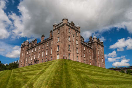 Holm of Drumlanrig, Scotland, UK - June 18, 2012: Closeup of free standing pink sand stone Drumlanrig Castle on its higher plateau under cloudy sky.のeditorial素材