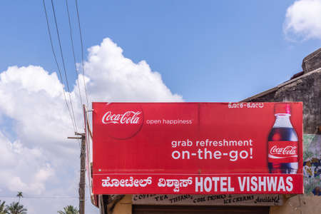 Belur, Karnataka, India - November 2, 2013: Red billboard at entrance of Hotel Vishwas displays Coca-Cola advertisement under blue sky with white clouds.のeditorial素材