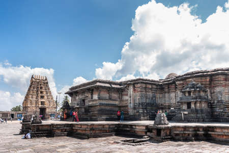 Belur, Karnataka, India - November 2, 2013: Chennakeshava Temple. Brown stone Gopuram of main entrance in back with Kesava sanctuary up front under blue sky with white clouds. People add color.のeditorial素材