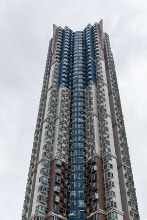 Hong Kong, China  - May 12, 2010: Closeup of very tall slender gray tower with small apartments set...