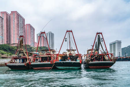 Hong Kong, China  - May 12, 2010: Four black and red fishing vessels docked in  harbor with pink...