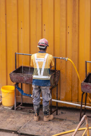 Hong Kong Island, China  - May 14, 2010: Construction worker at second International Finance Center washes hands. Yellow wall in back. helmet, boots and work clothes.のeditorial素材