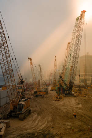 Hong Kong Island, China  - May 14, 2010: Plenty of yellow cranes on new construction site adjacent to Two International Finance Centers. Against foggy brownish sky.  Couple of penetrating sunrays.のeditorial素材